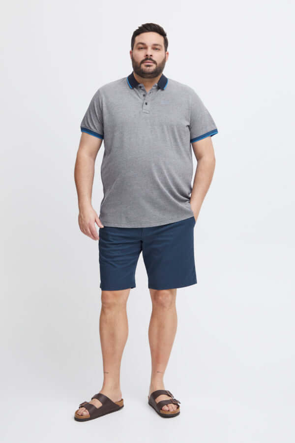 Model in Blend Polo Grote Maten blauw met knoopsluiting, gecombineerd met navy shorts en sandalen.