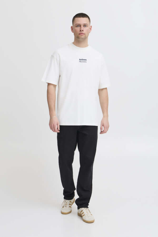 Man in een witte Blend T-Shirt met print, draagt zwarte broek en sneakers, casual uitstraling.
