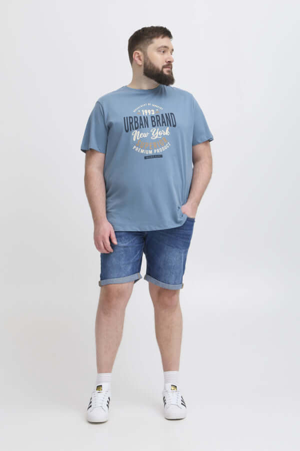 Model in blauwe Blend T-Shirt met opdruk, gecombineerd met denim shorts en sneakers.