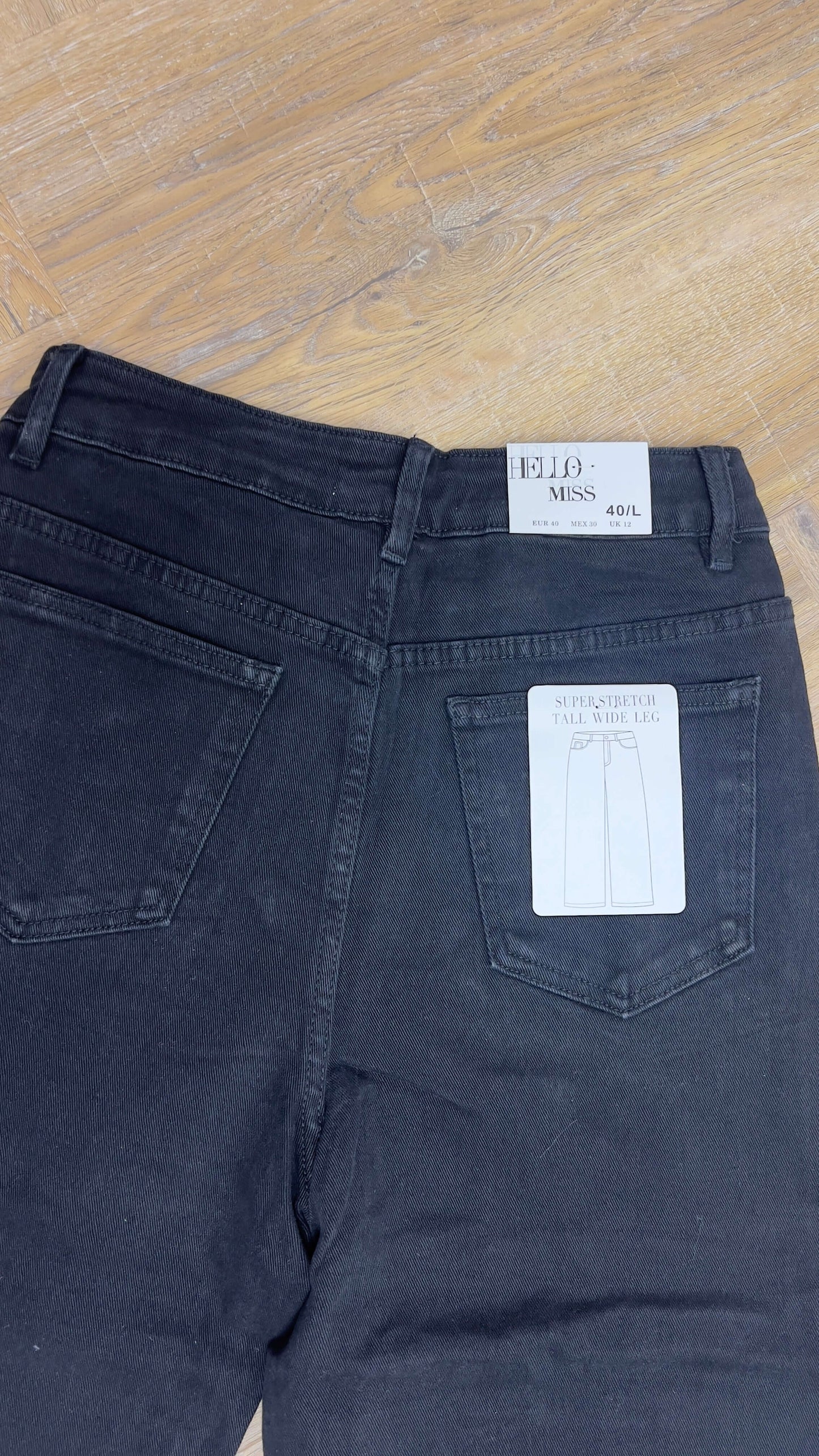 Hello Miss – Wide Leg Zwart – achteraanzicht van de zwarte wide leg jeans met label en zakken.