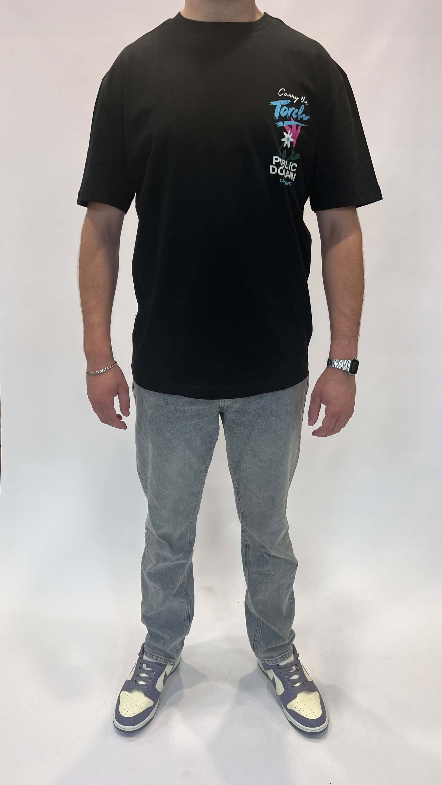 Model in zwart T-shirt met opdruk en grijze jeans, casual stijl voor dagelijks gebruik.
