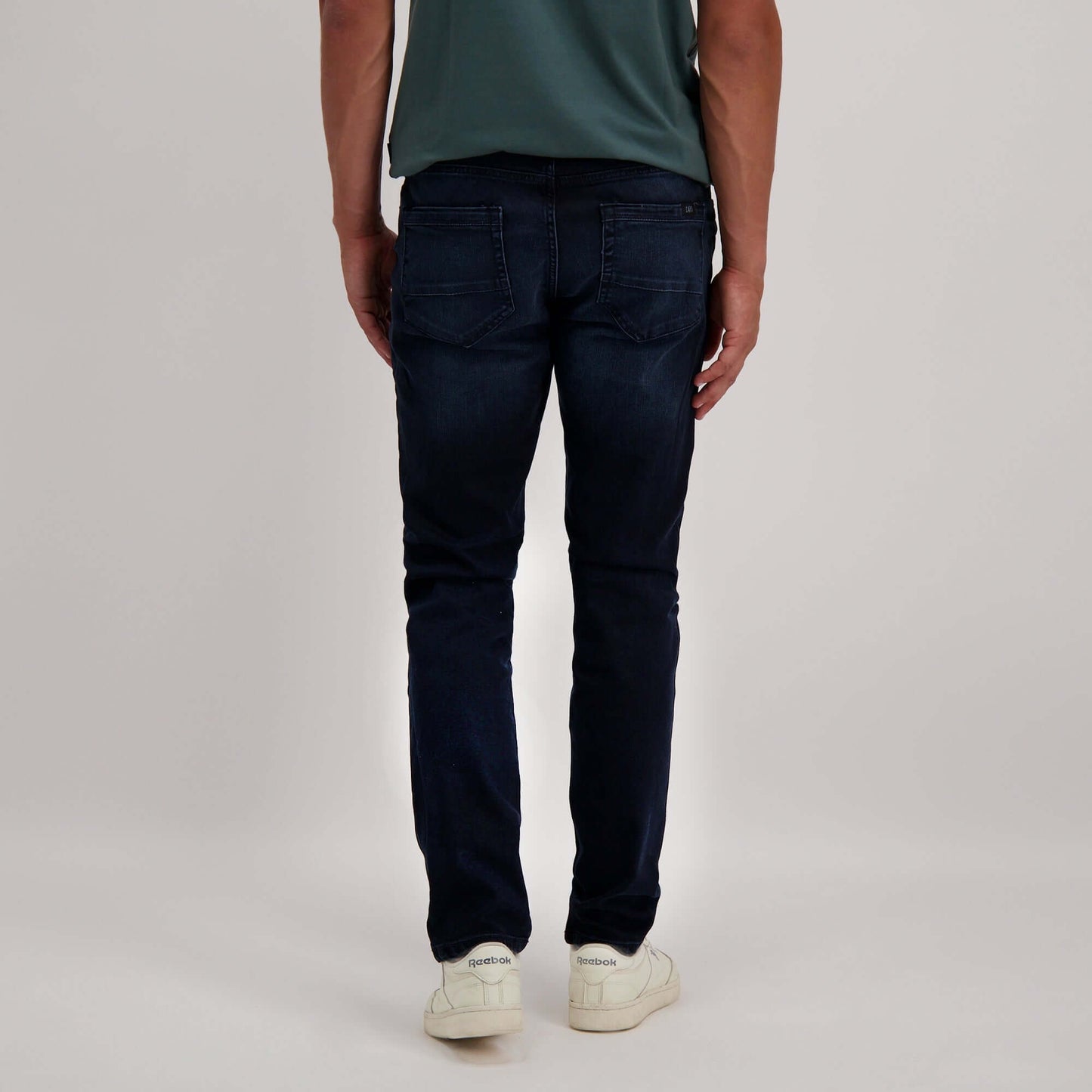 Achteraanzicht van de Cars Jeans Douglas in donkerblauw, gedragen met een groen shirt en witte sneakers.