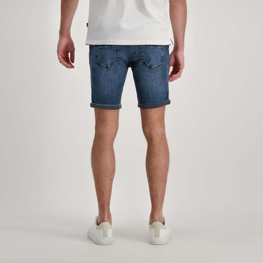 Achteraanzicht van een man in een korte jeans broek, casual en comfortabel voor warme dagen.
