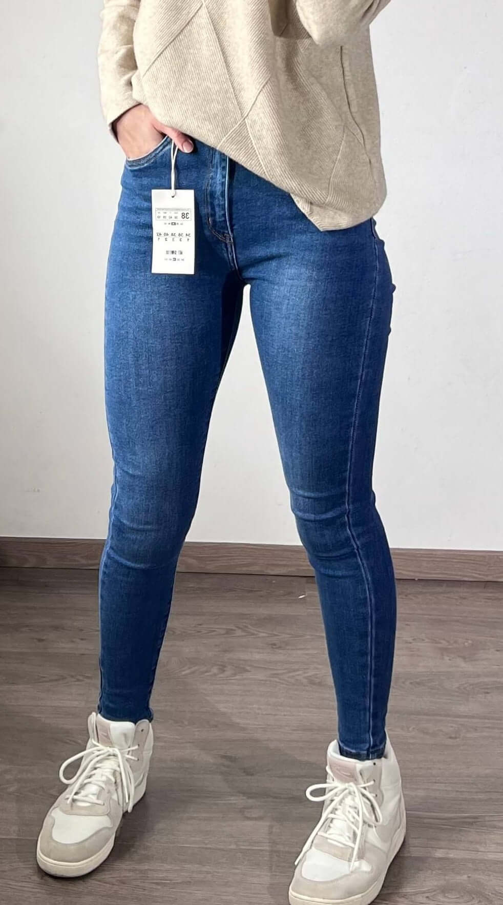 Model in medium blue VS Miss skinny jeans met hoge taille en sneakers, ideale casual outfit.